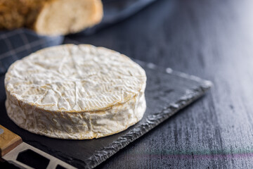 Camembert cheese on black table. French cheese with mold on the surface.