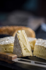 Camembert cheese on black table. French cheese with mold on the surface.