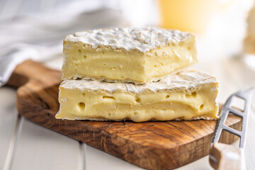 Camembert cheese on wooden cutting board. French cheese with mold on the surface.