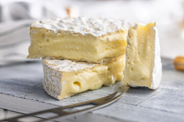 Camembert cheese on cutting board on white table. French cheese with mold on the surface.