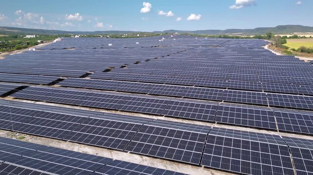 Drone view of expansive photovoltaic solar panel installation in rural agricultural area, renewable electricity generation plant supplying sustainable green energy for environmental protection and cli