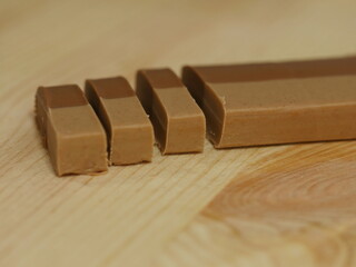 Piece of chocolate is cut into four pieces and placed on a wooden table