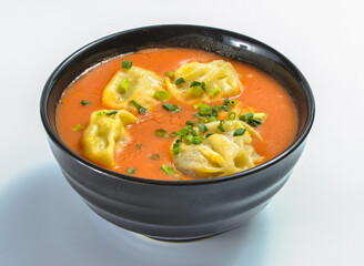 Spicy Soup Momos topped with green green onions in a Black Bowl isolated on white background side view of South Asian cuisine
