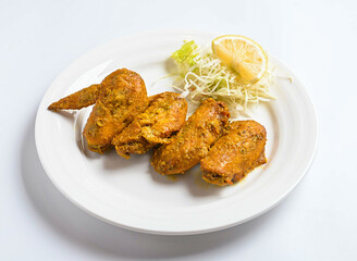 Spicy Grilled Chicken Wings on a Plate Garnish with lemon and cabbage isolated on white background top view of Pakistani food