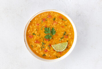 Red lentil soup with spices and fresh herbs on a gray background. Indian dal soup. Top view