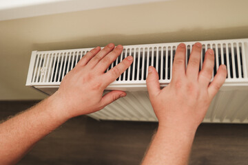 Hands gently placed on a warm radiator, checking the heat level in a cozy home. The image highlights comfort, heating performance, and the importance of reliable heating systems. High quality photo