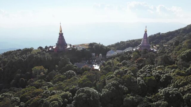 Pagodas stand atop a lush, green mountain range in chiang mai, thailand