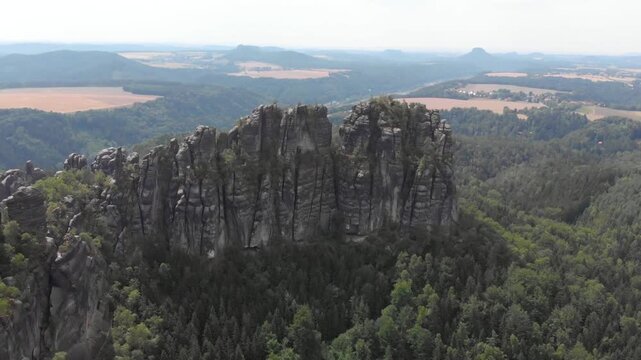 Dramatic rock formations rise above a lush forest in saxon switzerland, germany