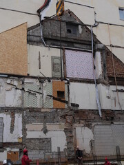 Building with a lot of damage and a man sitting on the sidewalk