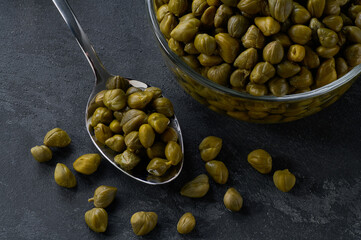 pickled caper berries on a black stone table, top view.