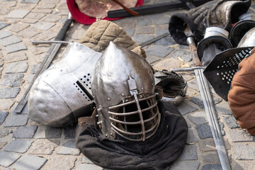 Medieval armor pieces and swords on cobblestone ground