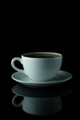 Minimalistic photo of a coffee cup on black background with reflection
