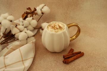 Warm drink served in a unique mug with cinnamon and cotton accents in a cozy setting