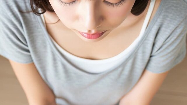 部屋で床に座り、潤んだ瞳でこちらを見上げるTシャツ姿の女性
