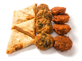 Indian style starter food selection of samosa, bhajis and pakoras on white background. Party sharing finger food variety made from fine products and aromatic spices. Special orient vibe.
