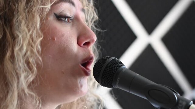 Caucasian woman singing into microphone in music studio. 