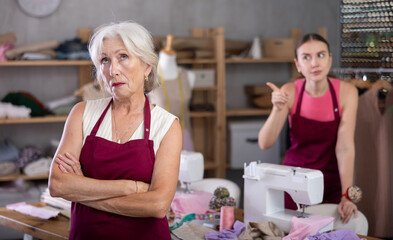 Woman head of sewing workshop yells at her subordinate senior female seamstress, scolds for improper performance of duties. Work conflict, toxic relationships in team..