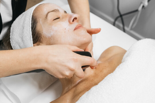 Woman receiving RF lifting treatment for facial rejuvenation, with a professional applying a device to enhance skin texture and promote youthful appearance in a serene spa environment