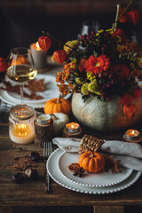 Atmospheric autumn elegant beautiful table setting with pumpkins for a wedding or thanksgiving family celebration. Fall decoration countryside rustic style, cozy home atmosphere , candles, wine