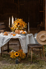 Beautiful fancy fall wedding table decor, countryside style cottage core. Vintage wooden furniture, candlelight, centrepiece with natural sunflowers. Cozy atmosphere, autumn vibes, stylish house decor
