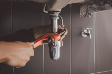 plumber at work in a bathroom, plumbing repair service , fix water plumbing leaks, replace the...