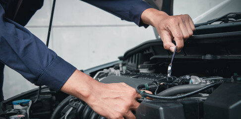 Mechanic using wrench while working on car engine outside the service center , Repair and service.