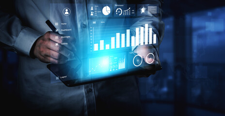 A businessman engages in data analysis using a digital tablet in a modern office. Visible business graphics and charts enhance the display, representing insights and trends. Impute