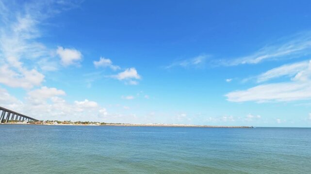 Blue sea meets the horizon under a bright, clouddotted sky on a sunny day