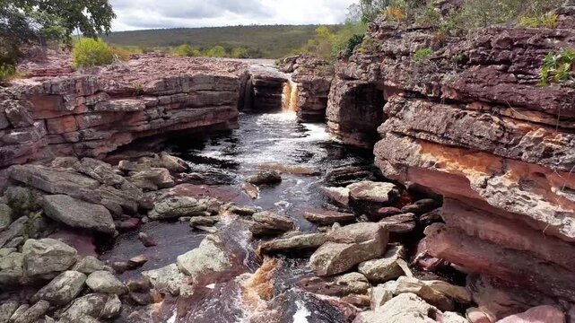 Water cascades through a narrow gorge carved into red rock formations
