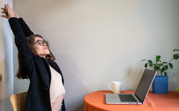 Relaxed businesswoman stretching arms home office workspace remote work coffee break mental health self care productivity wellness concept. - Powered by Adobe