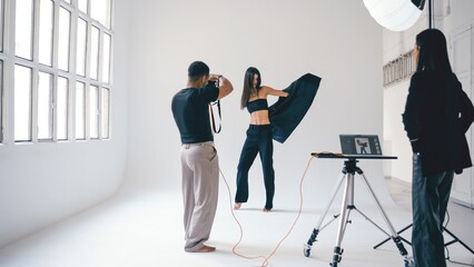Photographer taking pictures of fashion model posing in studio