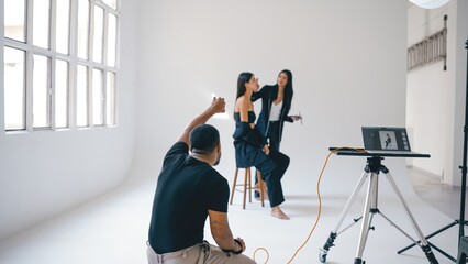 Photographer directing model and makeup artist during photoshoot in studio