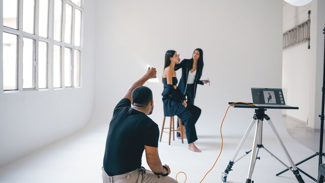 Photographer directing model and makeup artist during photoshoot in studio