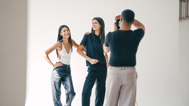 Photographer taking pictures of two fashion models in studio