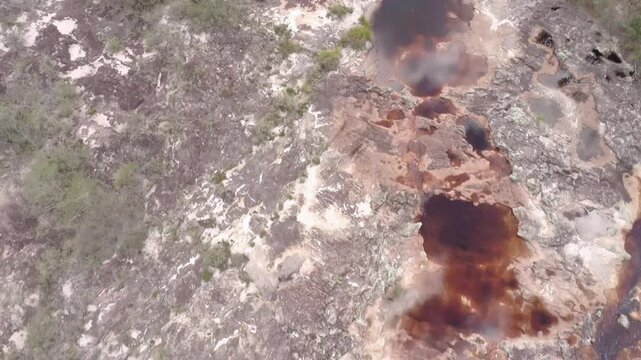 Water flows over rustcolored rocks, creating a textured and mineralrich landscape