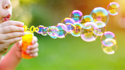 Child having fun outdoors in summer, blowing colorful soap bubbles, enjoying carefree playtime and simple childhood pleasure in green park