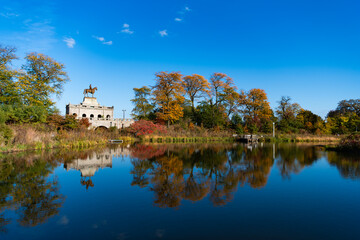 Fototapeta premium City park with water reflection lake. Autumn landscape nature. Park pond. Park in autumn with colorful fall trees. Autumn nature. Fall nature landscape. Lake in park with autumn tree