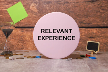 RELEVANT EXPERIENCE text on notebook with pen, calculator and chart on a grey background.