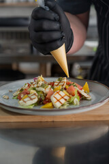 The chef seasons the salad with sauce. 