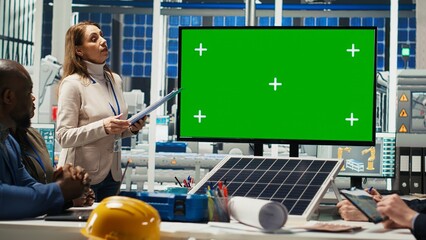 Businesspeople in photovoltaics plant look at data on mockup display. Solar panels factory management team and investor displaying deal terms on green screen monitor, camera B