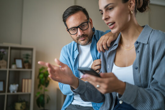 Couple discussing content on smart phone at home