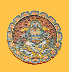 Round carved wooden buddhist deity depiction on yellow background