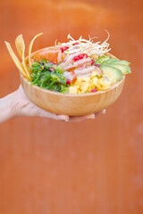 Exotic poke bowl with salmon, shrimp, avocado and mango in wooden bowl
