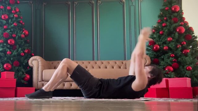 homem faz exerc&iacute;cios f&iacute;sicos para abdomen na sada de casa pronta para o natal 