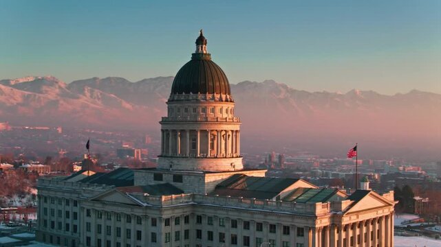 The utah state capitol building stands tall against a backdrop of snowy mountains