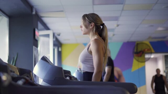 Cardio fitness: Focused female athlete using a modern automated treadmill for brisk walking
