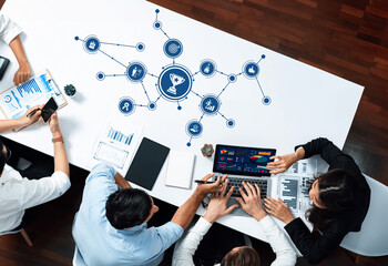 A diverse team collaborates in a modern office environment, engaging in a strategic discussion with data visualization on a laptop, showcasing teamwork and innovation. Amity