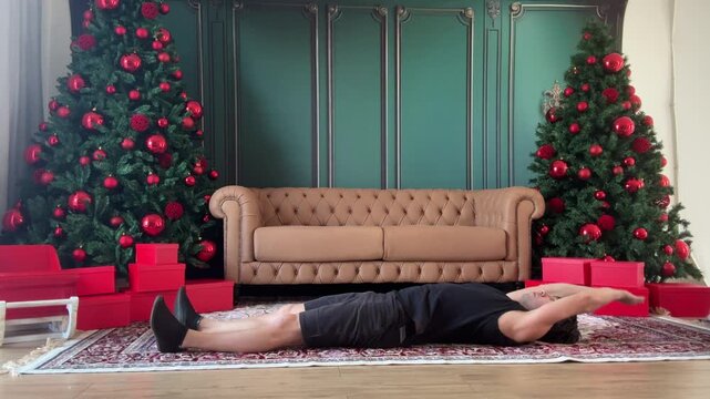 homem faz exerc&iacute;cios f&iacute;sicos para abdomen na sada de casa pronta para o natal 