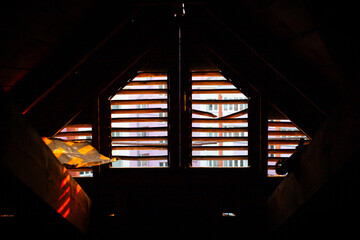 A view of the sunset from the attic through a loft window for ventilation, a beautiful red sunset in backlight