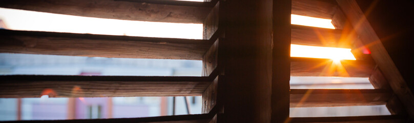 A view of the sunset from the attic through a loft window for ventilation, a beautiful red sunset in backlight